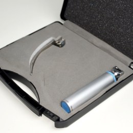 Відкритий кейс з ларингоскопним набором: у ложементі окремо лежать металева рукоятка та вигнутий клинок типу Macintosh